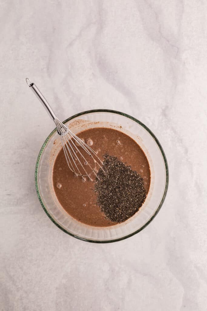Chia seeds added to the chocolate mixture in a glass bowl before whisking