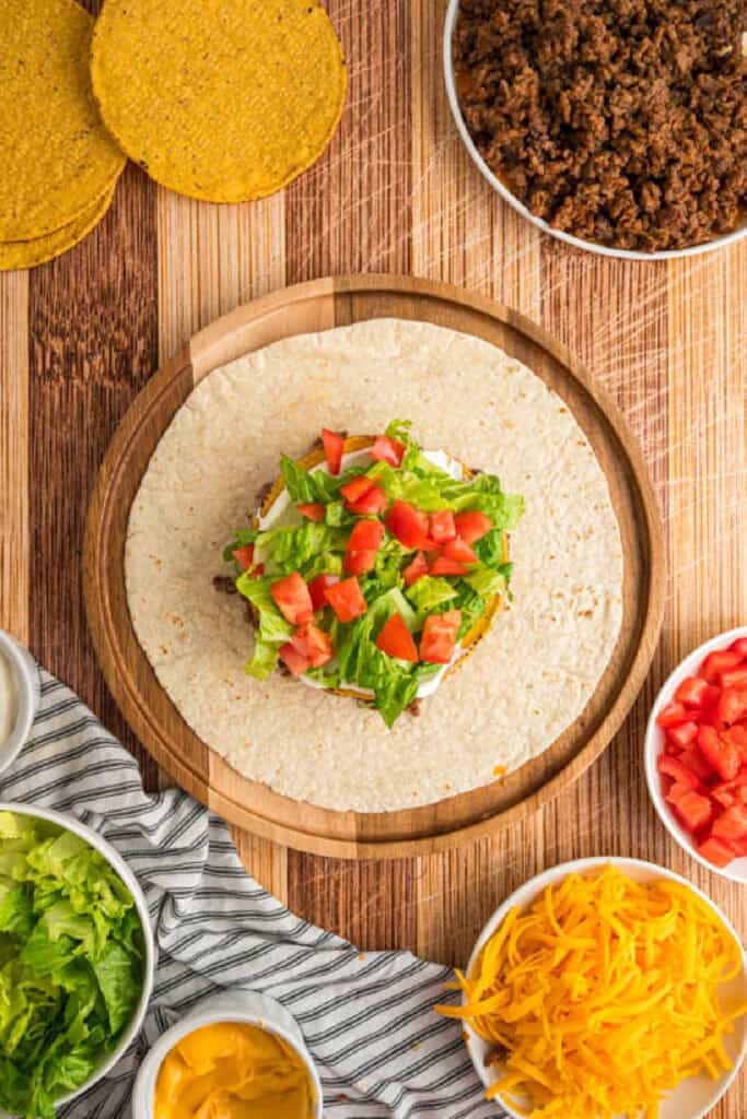 Chopped tomatoes added over lettuce in a homemade Crunchwrap