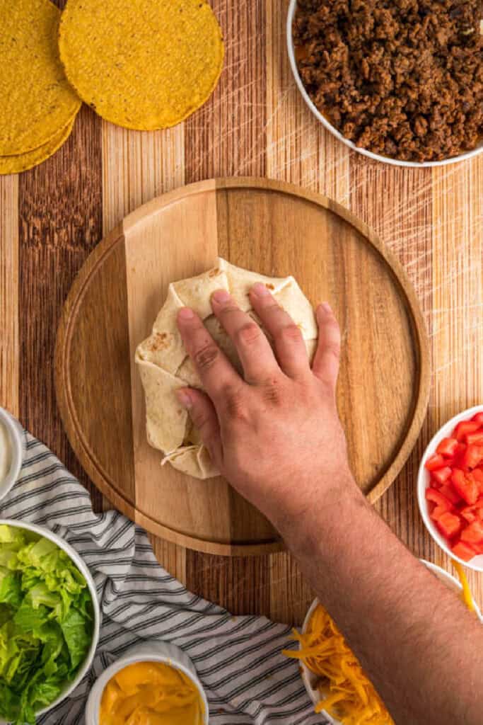 Folding the flour tortilla into pleats around the Crunchwrap filling