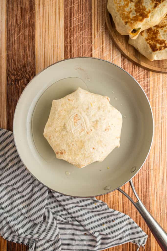 Folded Crunchwrap cooking seam-side down in a skillet