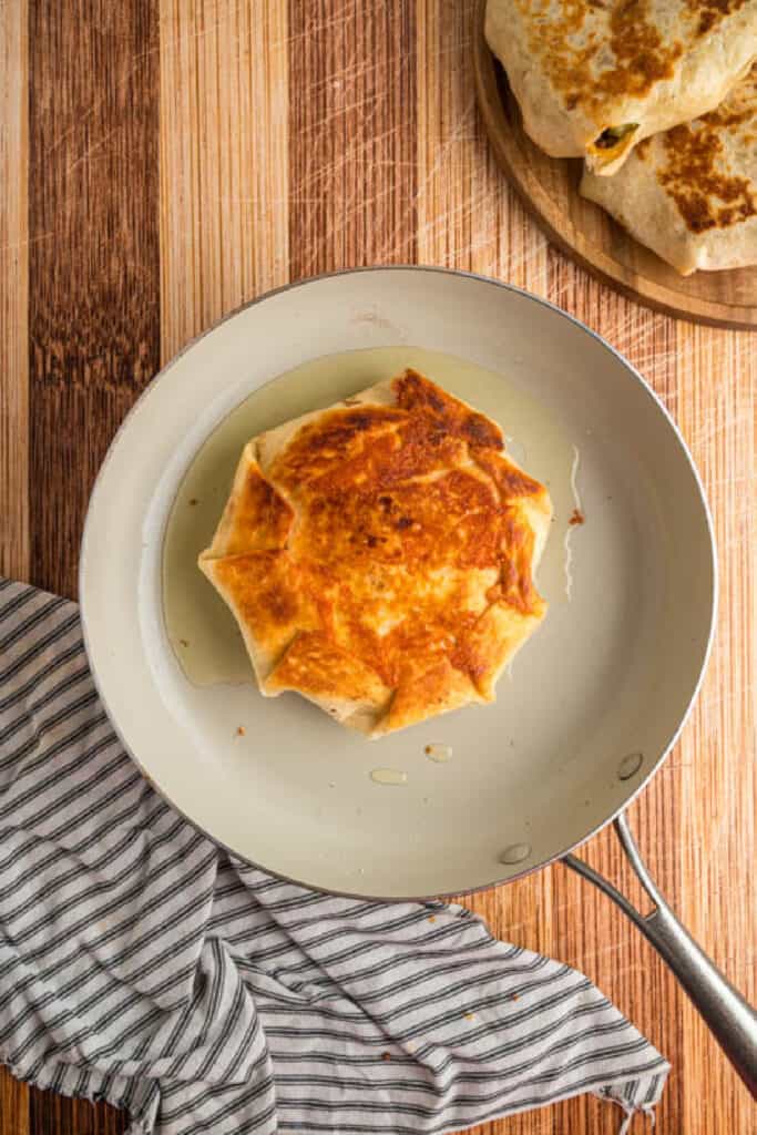 Golden brown Crunchwrap Supreme cooking until crispy in a skillet