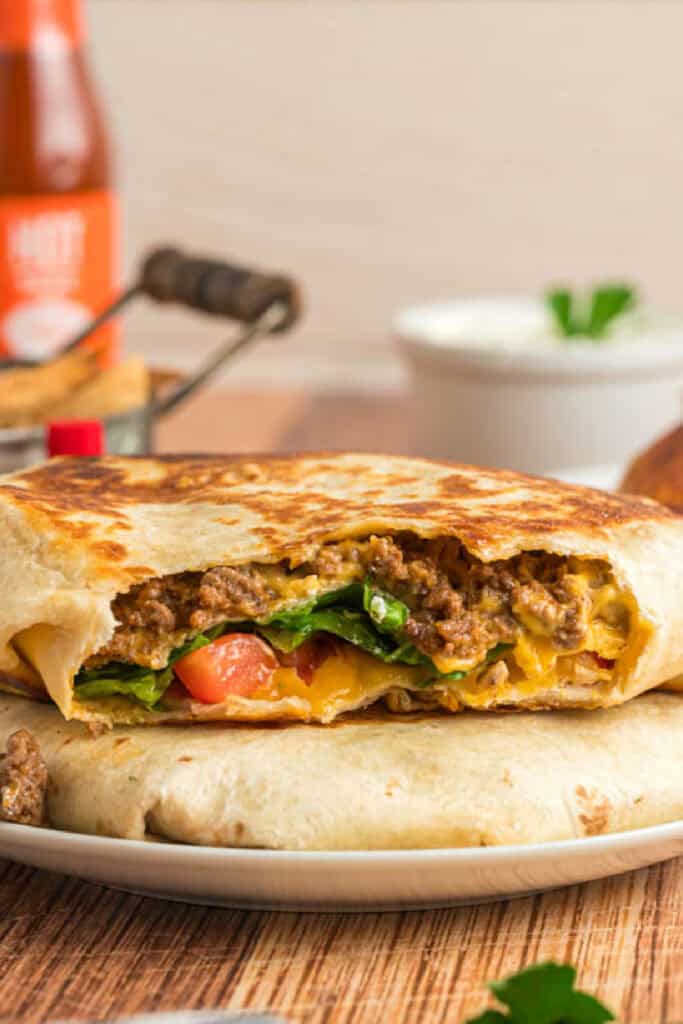 Homemade Crunchwrap Supreme cut open to show seasoned beef, cheese, lettuce, and tomatoes