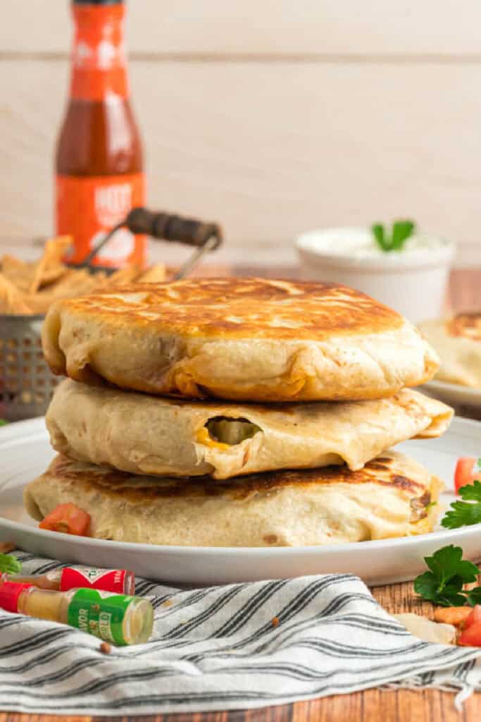Three crispy homemade Crunchwrap Supremes stacked on a serving plate