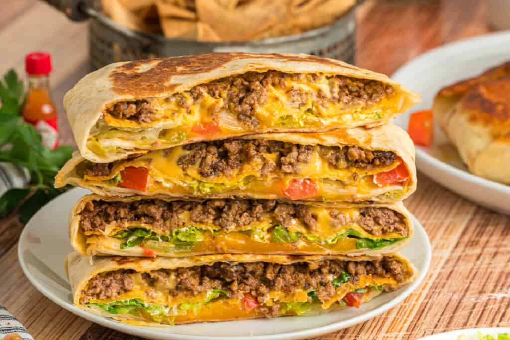 Four Crunchwrap Supreme halves stacked to show the cheesy ground beef and fresh vegetable filling