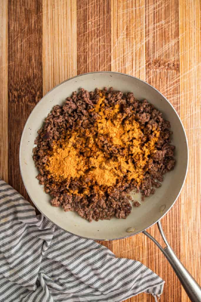 Taco seasoning added to browned ground beef in a skillet