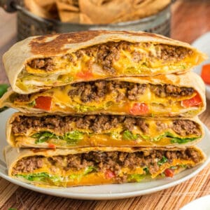 Crunchwrap Supreme stacked with seasoned ground beef, melted cheese, lettuce, and tomatoes visible inside