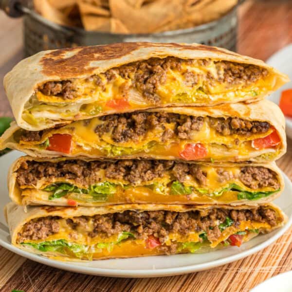 Crunchwrap Supreme stacked with seasoned ground beef, melted cheese, lettuce, and tomatoes visible inside