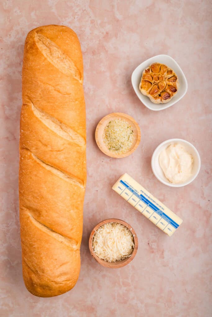 Ingredients for Grilled Garlic Bread including French bread, roasted garlic, butter, mayonnaise, Parmesan cheese, and garlic salt.