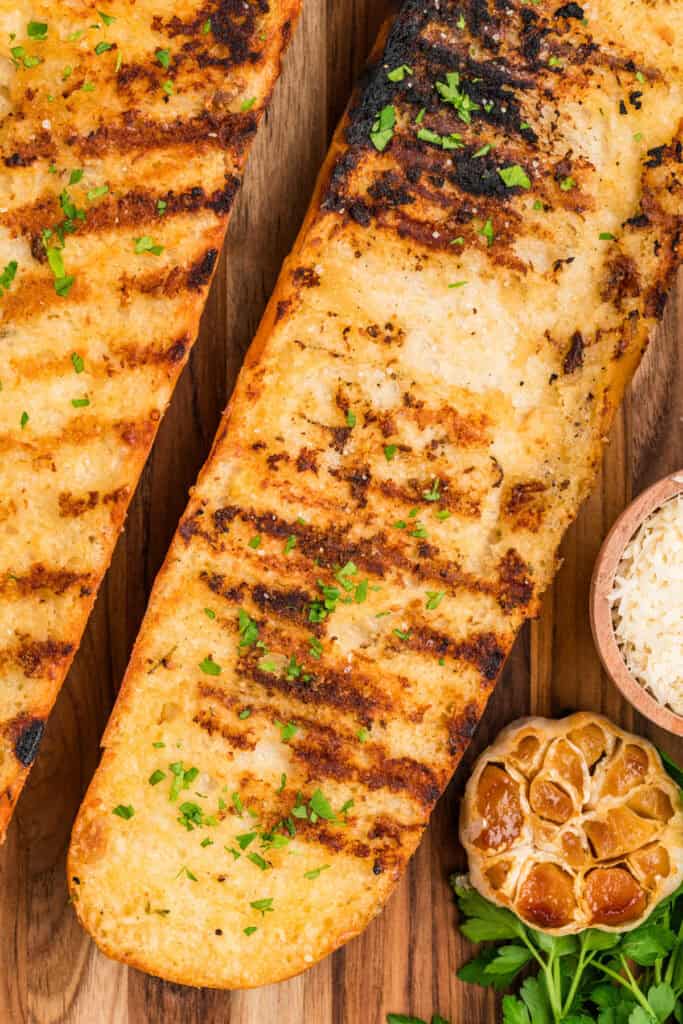 Close-up of Grilled Garlic Bread with crisp grill marks, roasted garlic, and fresh parsley garnish.