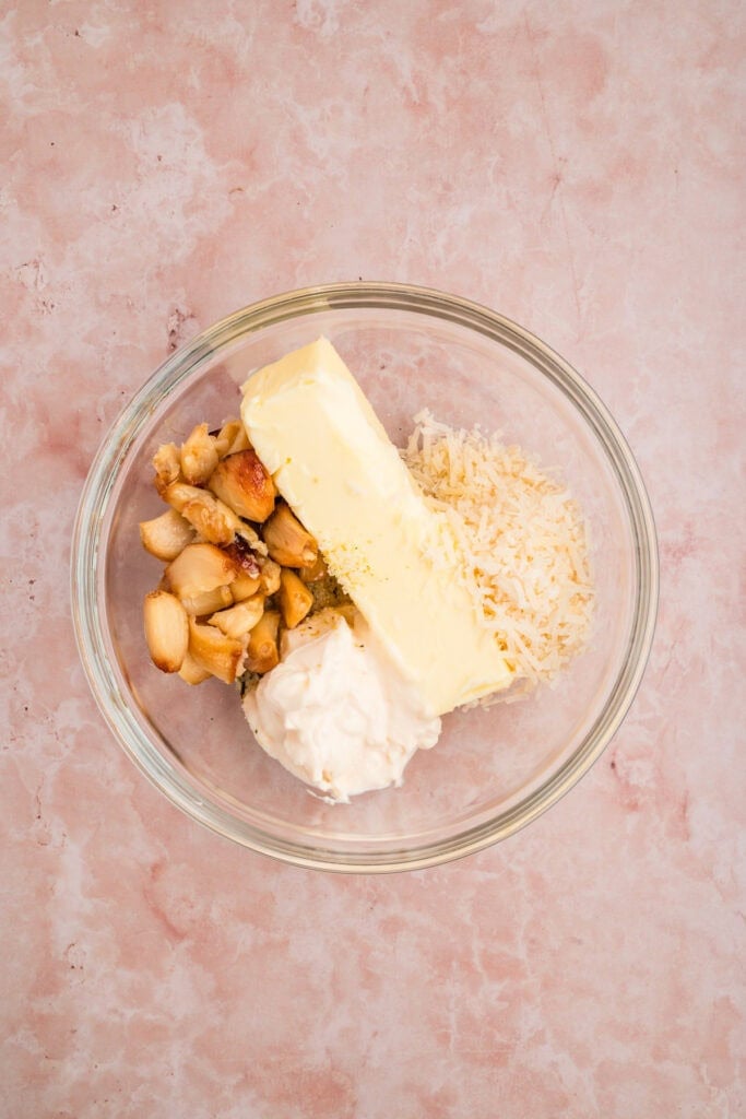 Butter, roasted garlic, mayonnaise, Parmesan cheese, and garlic salt in a bowl before mixing for Grilled Garlic Bread.