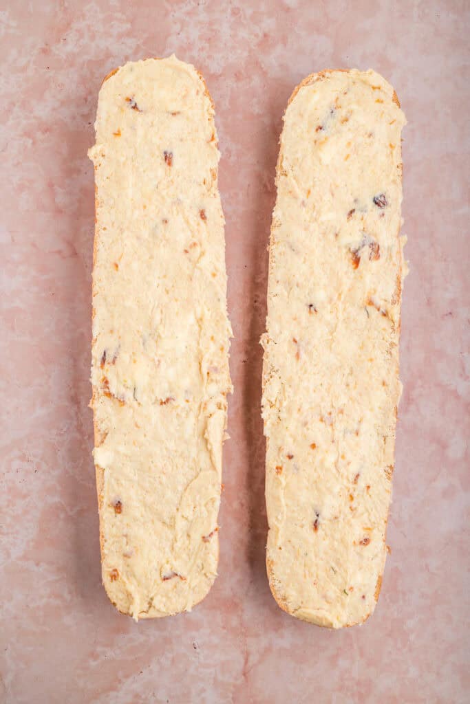 French bread halves evenly spread with roasted garlic butter before grilling.