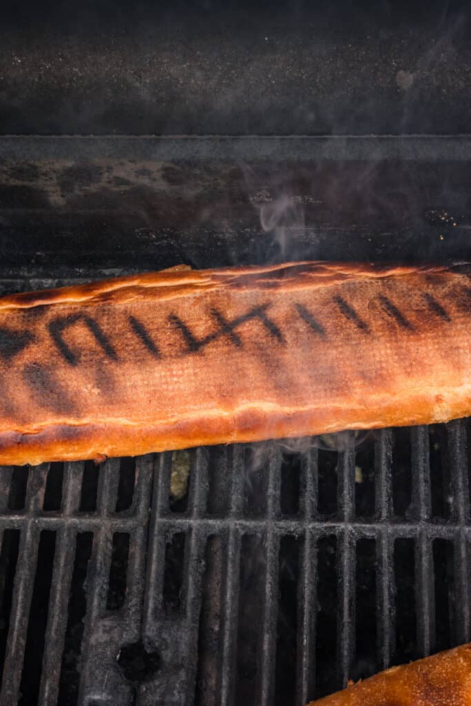 Grilled Garlic Bread cooking over direct heat with the bread flipped to create grill marks.
