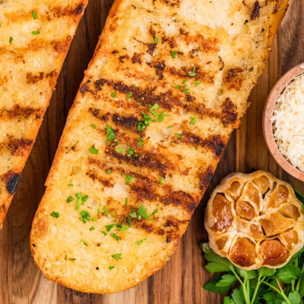 Square overhead photo of Grilled Garlic Bread served with roasted garlic, Parmesan cheese, and fresh parsley.