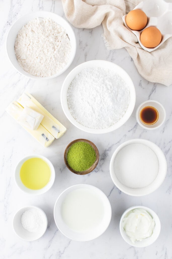 Ingredients for Matcha Cupcakes arranged in bowls on a white marble surface