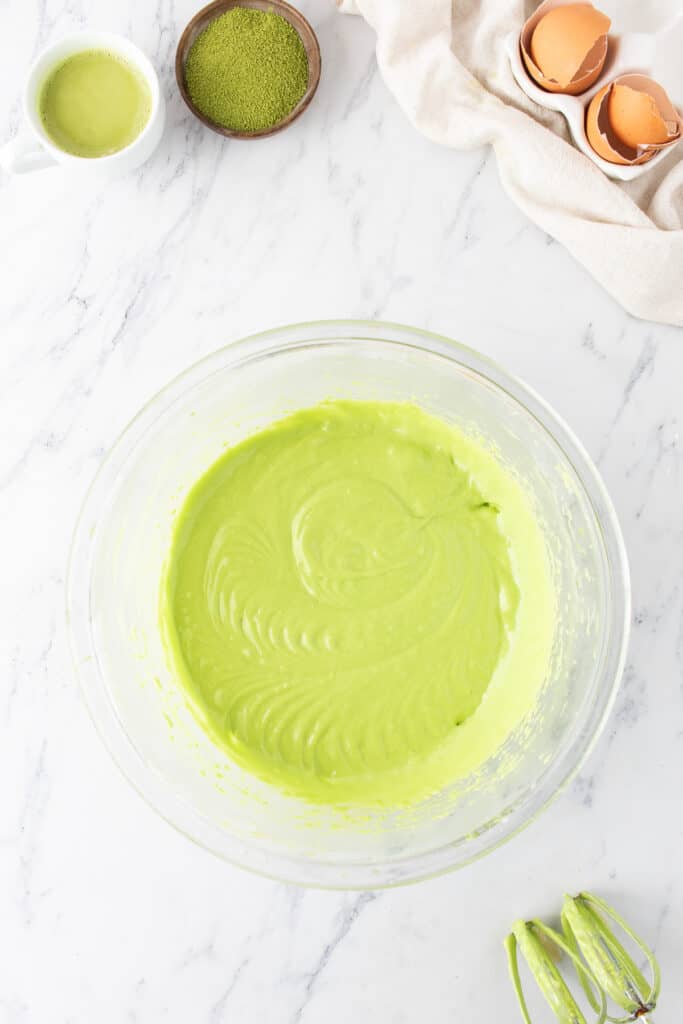 Smooth green matcha cupcake batter in a glass mixing bowl