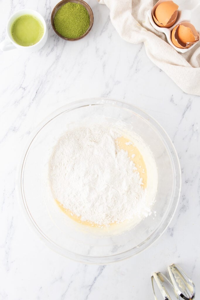 Dry flour mixture added to the wet cupcake ingredients in a glass bowl