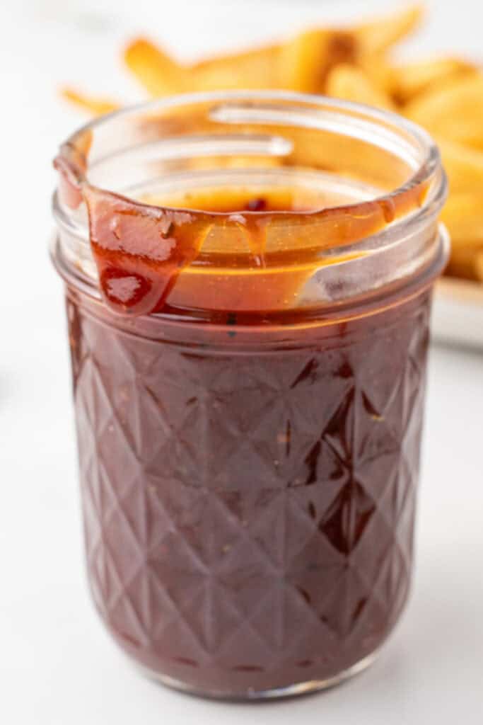 Homemade OMG Sauce stored in a glass jar with French fries in the background