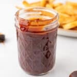 Glass jar filled with homemade OMG Sauce beside a plate of French fries