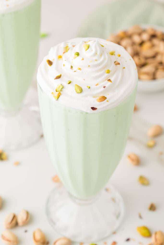 Close-up of whipped cream and chopped pistachios on top of a creamy pistachio shake