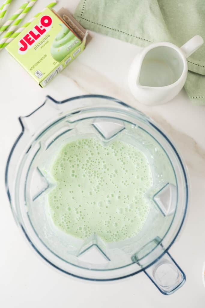 Pale green pistachio milkshake blended until smooth in a blender
