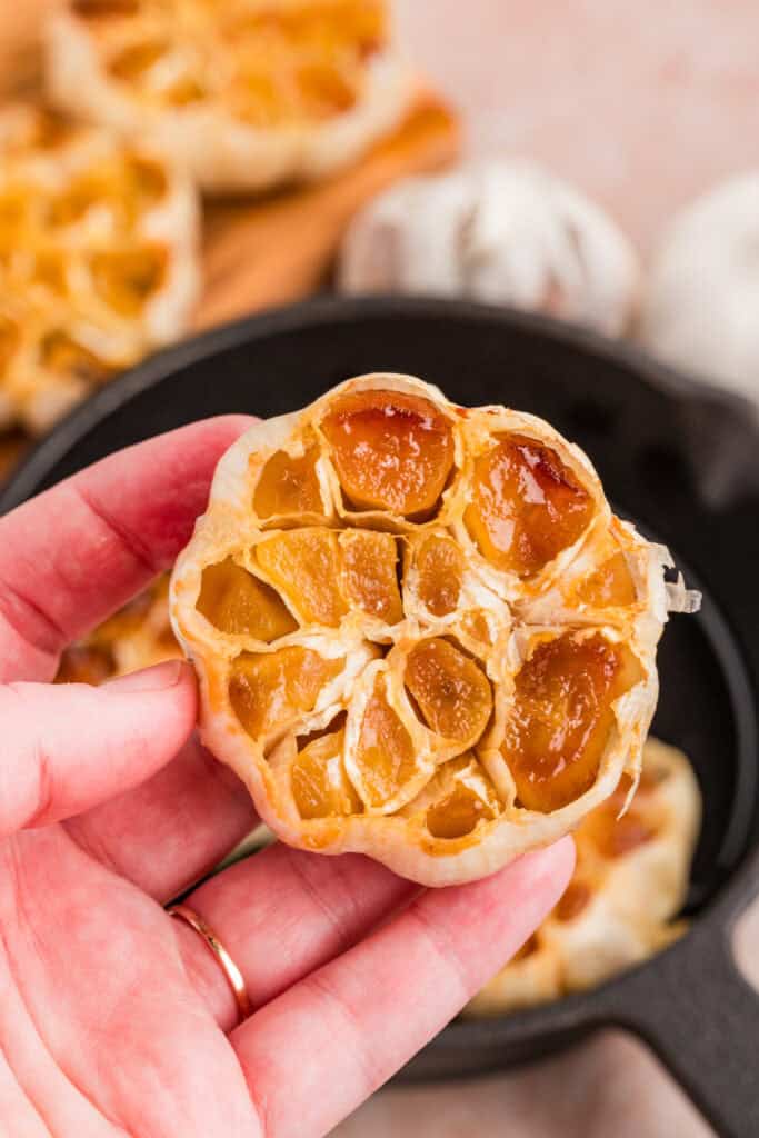 Whole bulb of roasted garlic held up to show the golden caramelized cloves