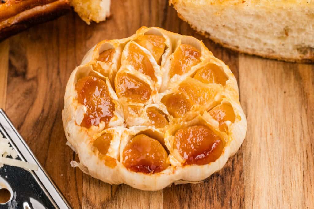 Roasted garlic bulb with soft golden cloves served alongside toasted garlic bread
