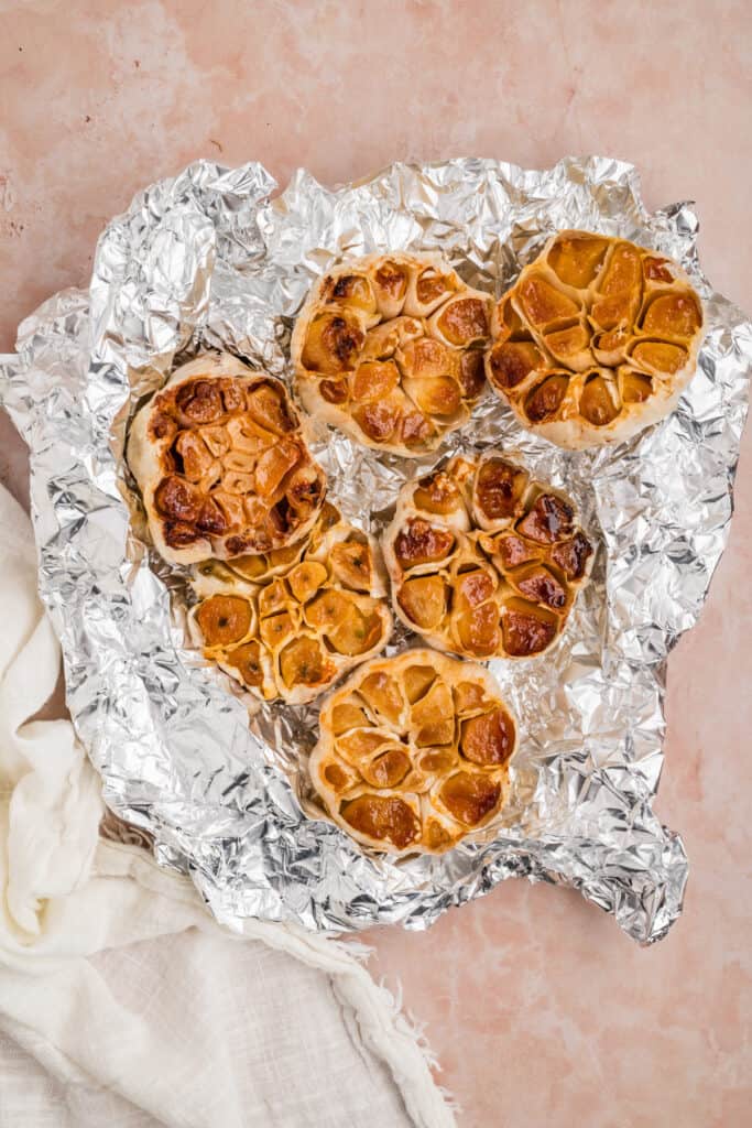 Several bulbs of roasted garlic unwrapped from foil after grilling