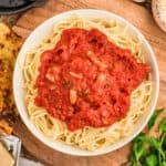 Roasted garlic pasta sauce served over spaghetti with garlic bread, Parmesan, and fresh herbs.