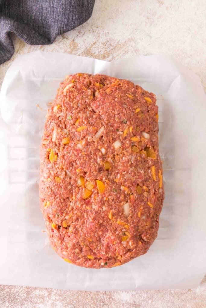 Raw cowboy meatloaf shaped into a loaf on parchment paper before smoking