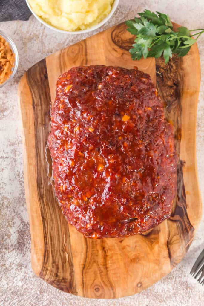 Glazed Smoked Cowboy Meatloaf resting on a round wooden serving board