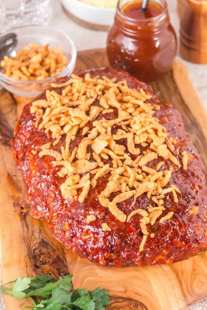 Smoked Cowboy Meatloaf topped with crispy onions on a wooden serving board