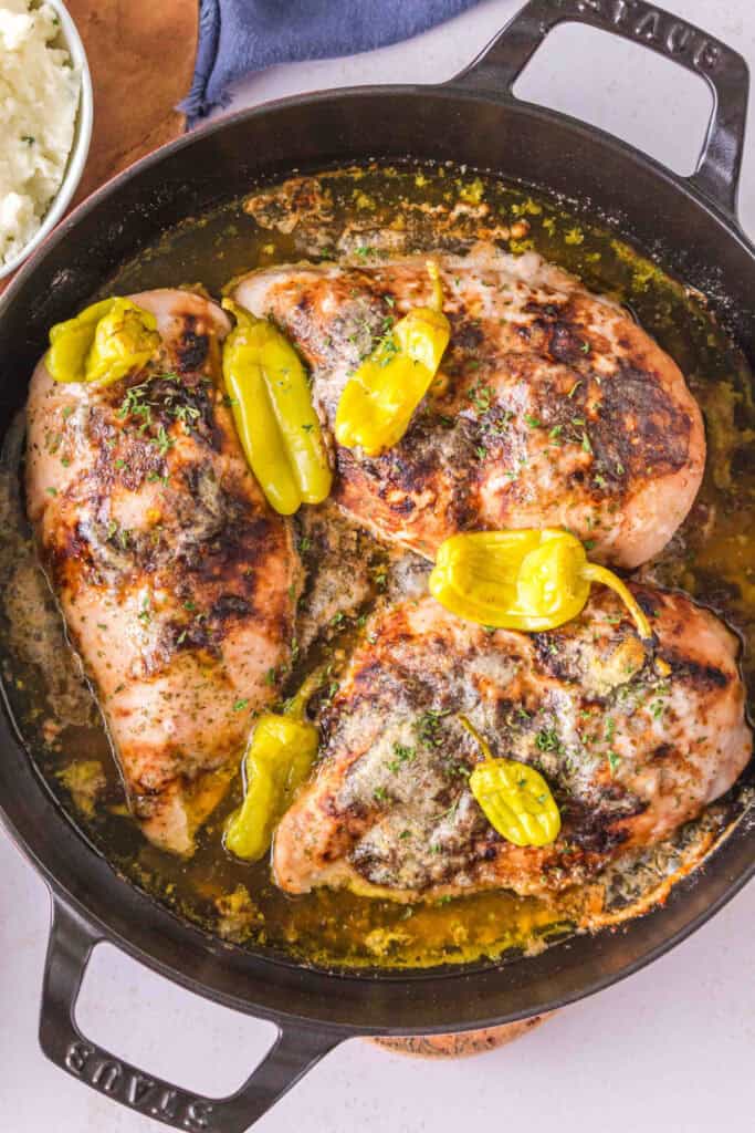 Finished smoked chicken breasts with pepperoncini and savory butter sauce in a cast iron skillet
