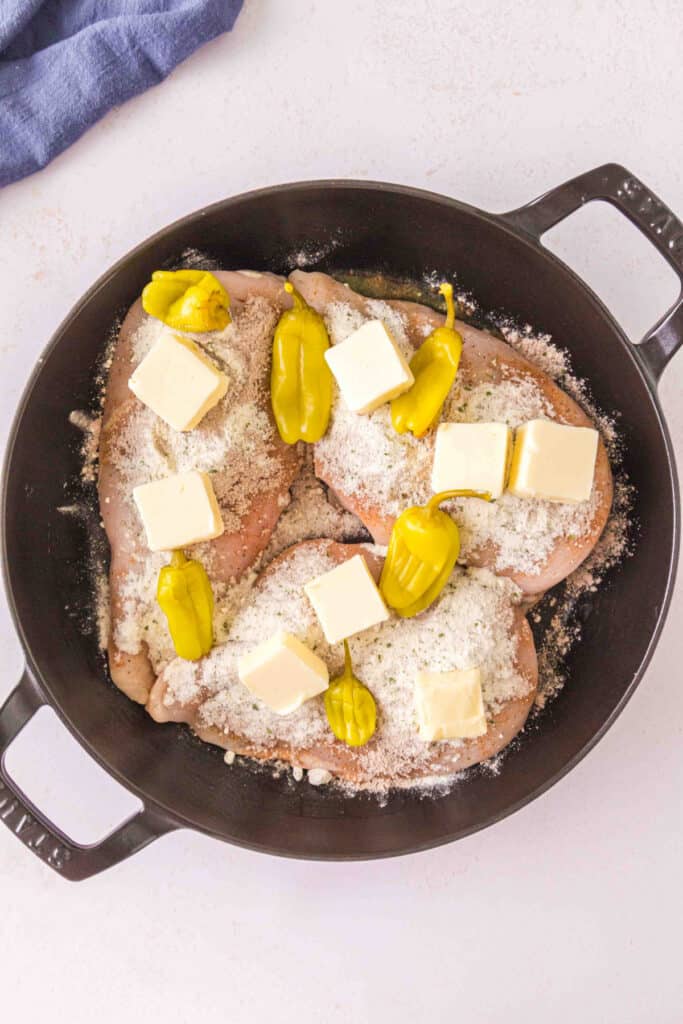 Seasoned chicken breasts topped with butter and whole pepperoncini before smoking