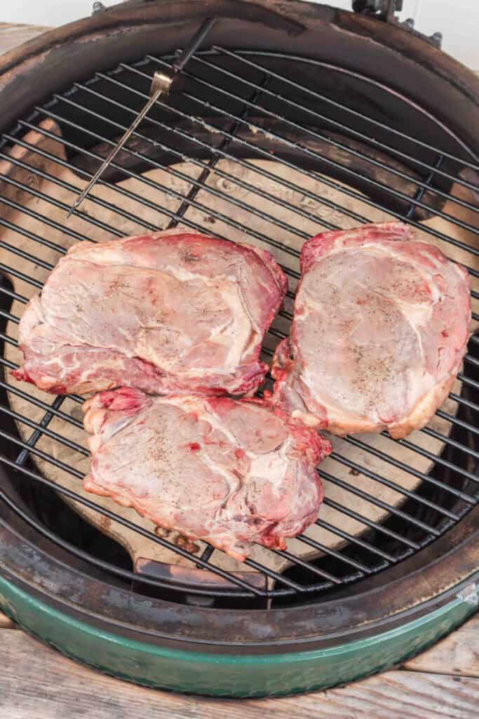 Ribeye steaks cooking slowly on the grill before the high-heat reverse sear.