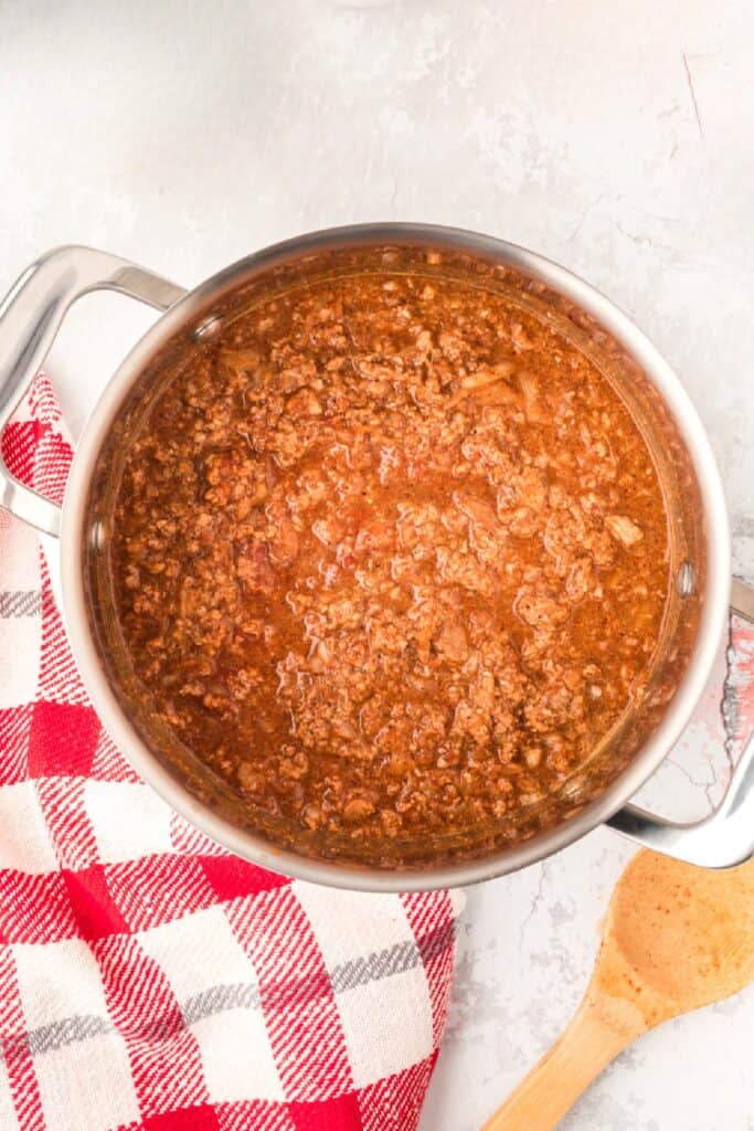 Pot of homemade Southern Style Hot Dog Chili with a wooden spoon beside the pan.