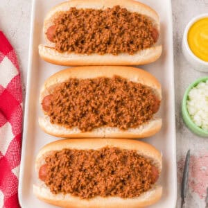 Close-up of three hot dogs topped with thick, meaty Southern Style Hot Dog Chili ready to serve.