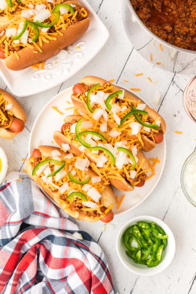 Texas Chili Dogs topped with chili, cheddar cheese, chopped onions, and sliced jalapeños