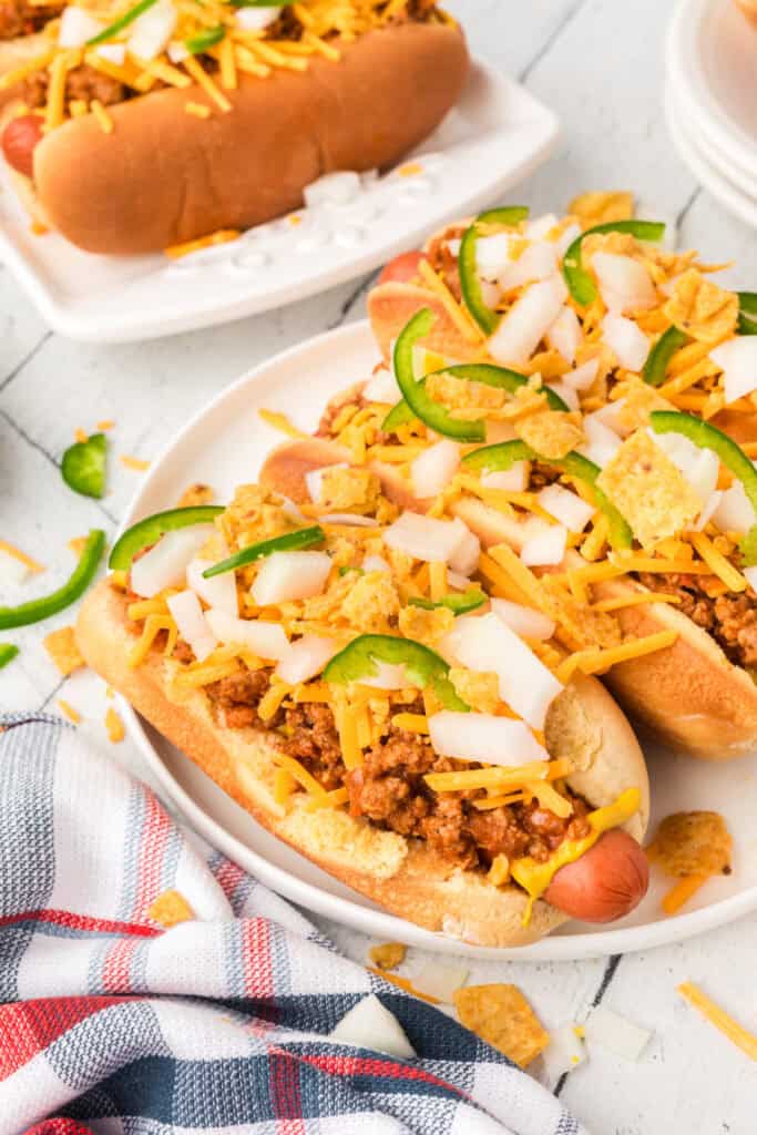 Close-up of Texas Chili Dogs with beef chili, cheddar cheese, onions, jalapeños, and crunchy corn chips