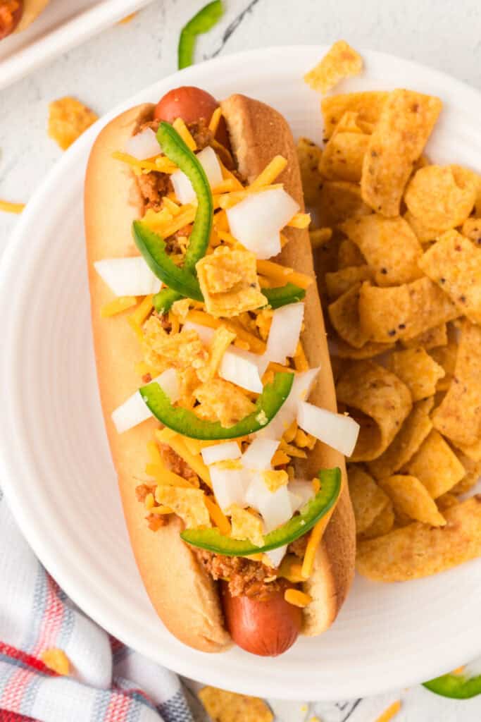 Overhead close-up of a Texas Chili Dog with chili, cheese, onions, jalapeños, and corn chips