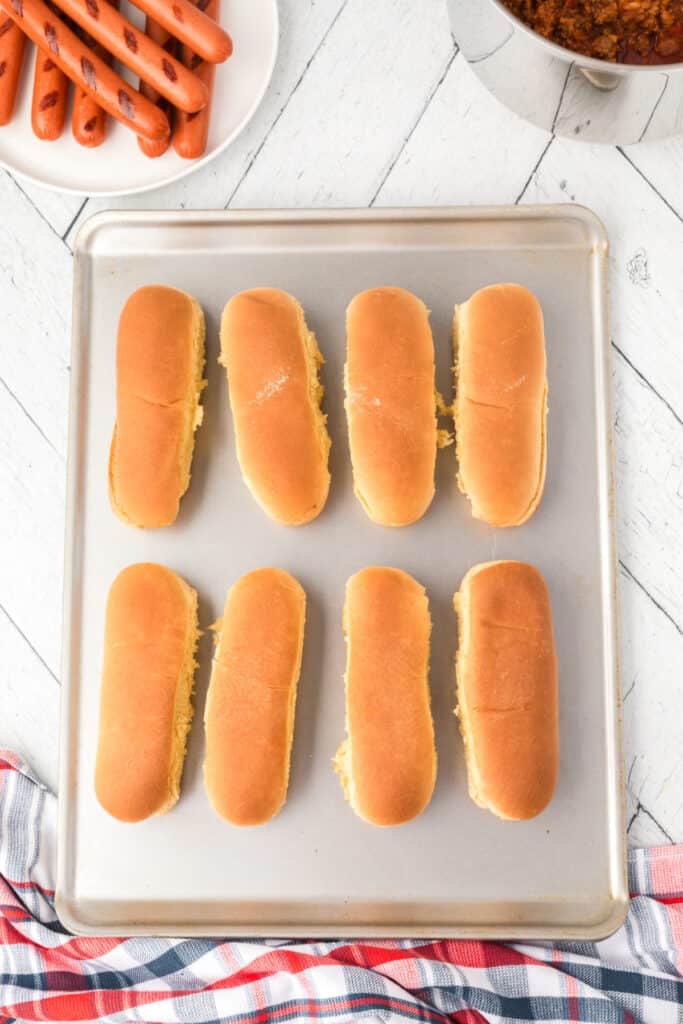 Hot dog buns arranged on a baking sheet