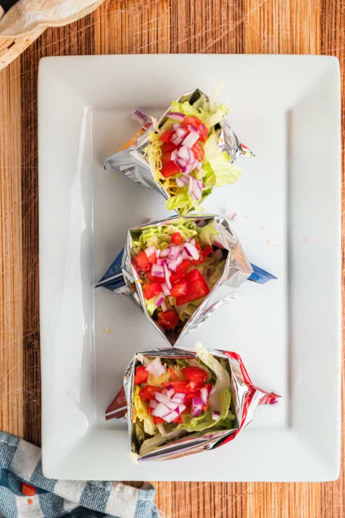 Diced red onion added over lettuce and tomatoes in Walking Tacos
