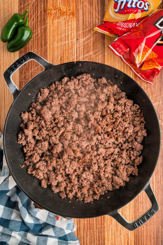 Ground beef browning in a large cast iron skillet for Walking Tacos
