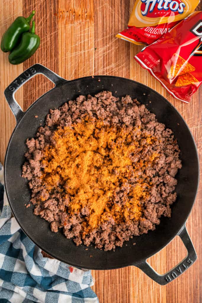 Taco seasoning sprinkled over cooked ground beef in a skillet