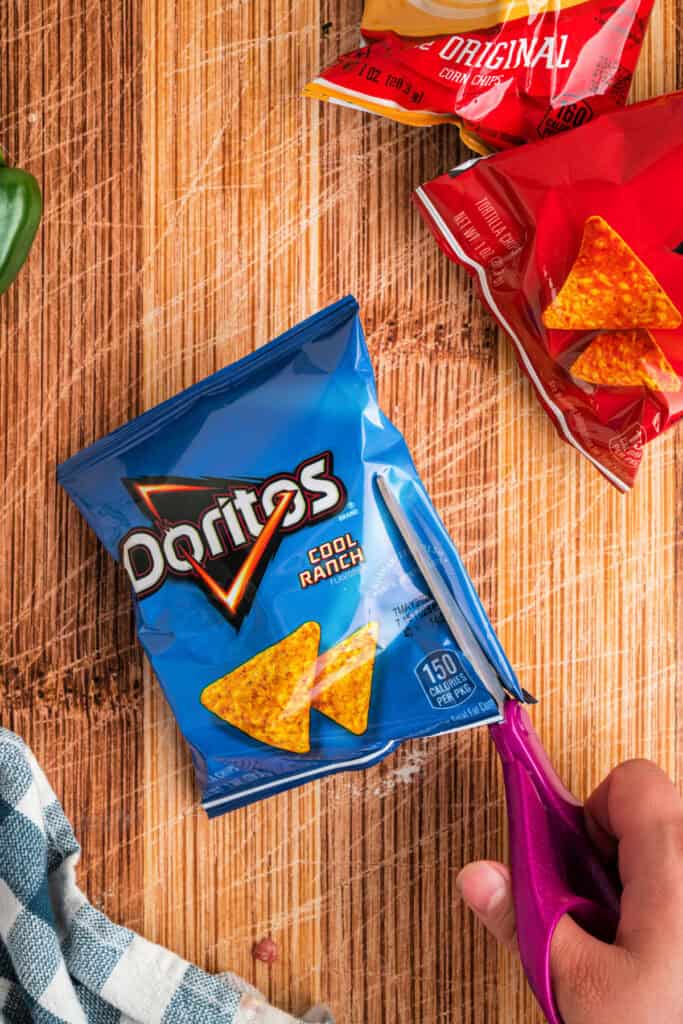 Cutting open an individual bag of corn chips along the side for a Walking Taco