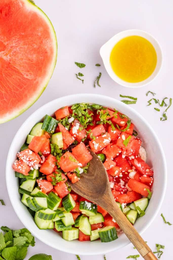 Watermelon Feta Mint Salad gently tossed with honey lime dressing in a white serving bowl.