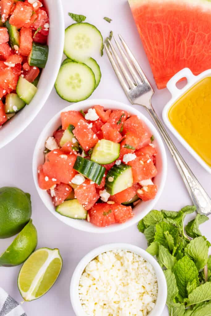 Individual serving of Watermelon Feta Mint Salad with cucumber, feta cheese, fresh mint, and honey lime dressing.