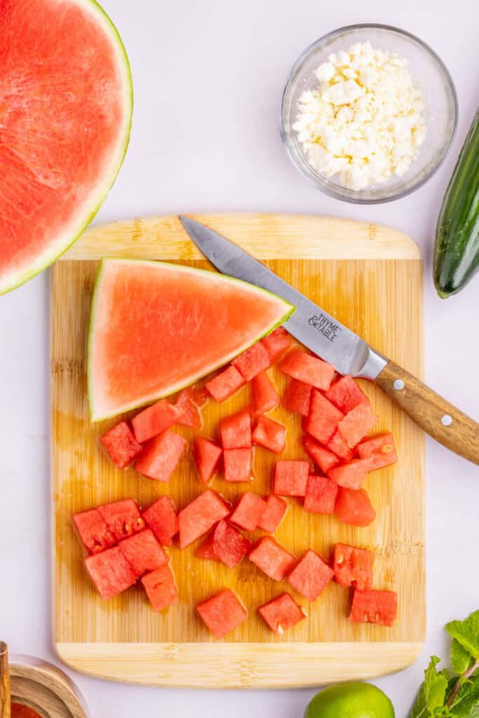 Cubed seedless watermelon being prepared on a cutting board for Watermelon Feta Mint Salad.