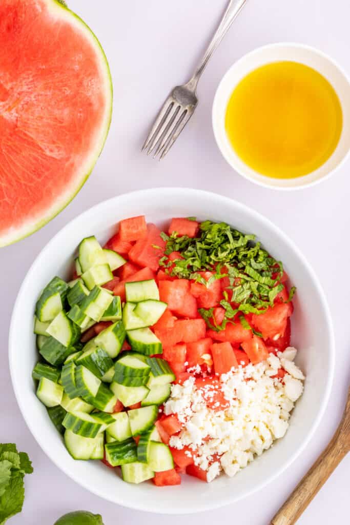 Watermelon, cucumber, feta, and fresh mint combined in a bowl before adding the dressing.