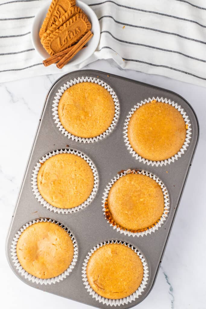 Freshly baked mini pumpkin cheesecakes cooling in a muffin pan before adding the cream cheese glaze.