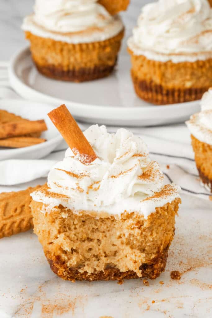 Cut mini pumpkin cheesecake showing the creamy pumpkin filling and Biscoff cookie crust beneath whipped cream.